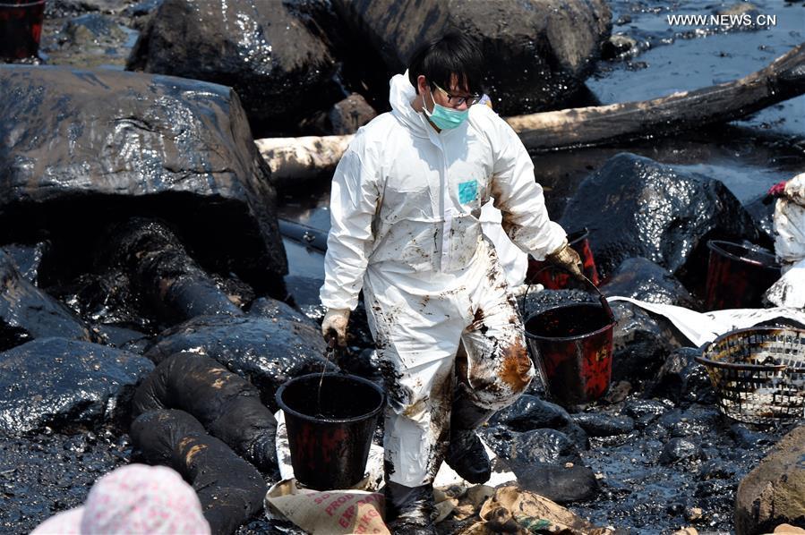 Workers clean up leaking oil on seaside of New Taipei city