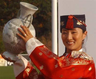 Hometown favorite Grace Park wearing a traditional Korean dress holds aloft her trophy after winning the CJ Nine Bridges Classic on Jeju Island, South Korea, Sunday, Oct. 31, 2004. South Korean Park fired a 7-under 65 in the final round to capture the title, five shots ahead of Sweden's Annika Sorenstam. [AP]