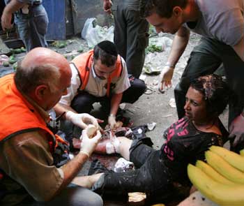 An injured woman receives first aid at the scene after an explosion in Tel Aviv November 1, 2004. An explosion rocked an open-air market in Tel Aviv on Monday, causing many casualties, the Magen David Adom ambulance service said. [Reuters]