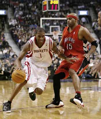 Houston Rockets guard Tracy McGrady (L) drives to the hoop past Toronto Raptors guard Vince Carter during the first half of their NBA game in Toronto, November 3, 2004. [Reuters]