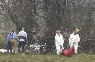 The remains of one of three people killed are removed from the site of a private jet crash as officials look through the debris Monday, Nov. 22, 2004, near Houston's Hobby Airport. The plane clipped a light pole and crashed a minute away from landing in a thick fog, killing all three crewmen. The plane was supposed to fly former President Bush to Equador from Houston. Bush has now canceled his trip.