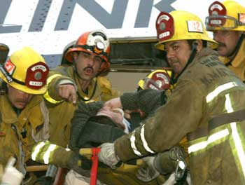 Los Angeles, Glendale and Burbank firefighters remove an injured passenger of a Metrolink train that collided and derailed in the Atwater Village area of Los Angeles, January 26, 2005. Ten people died and more than 200 people were injured when the train collided with a passenger car at a crossing, then hit two other trains as it derailed. 