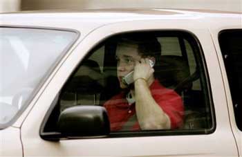 A motorist talks on a cell phone while driving Tuesday, Feb. 1, 2005, in Salt Lake City. According to a new study from the University of Utah, young motorists who talk on cell phones drive like elderly people, moving and reacting more slowly and increasing their risk of accidents. (AP 