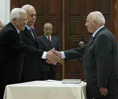 Palestinian Prime Minister Ahmed Qurie (R) is greeted by Palestinian President Mahmoud Abbas (L) during a swearing-in ceremony in the West Bank city of Ramallah, February 24, 2005. The Palestinian parliament approved on Thursday a cabinet of mostly new faces unassociated with the era of Yasser Arafat, signalling a commitment to reforms viewed as key to peacemaking. [Reuters]