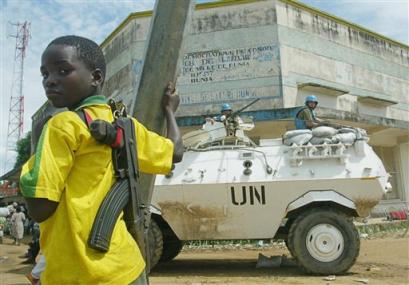 A child fighter of the rebel Union of Congolese Patriots stands near a United Nations armoured personnel carrier near the UN compound, in Bunia, Congo, in this May 30, 2003 file photo. Unidentified attackers ambushed U.N. peacekeepers on patrol in northeastern Congo on Friday, Feb. 25, 2005 leaving several of the troops dead, a U.N. spokesman said. [AP/file]