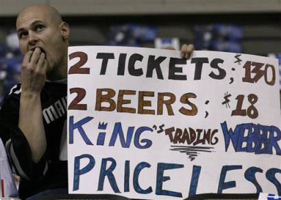 Before the start of the Sacramento Kings and the Dallas Mavericks game on Thursday, Feb. 24, 2005 in Dallas, Mavericks fan Israel Norcom, munches on popcorn and holds a sign expressing his delight with the Kings trade of Chris Webber to the Philadelphia 76ers. [AP]