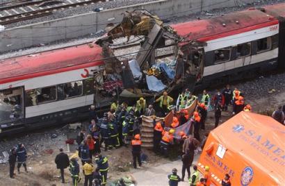Rescue workers cover up bodies by a bomb damaged passenger train following a number of explosions on trains in Madrid, Spain, in this March 11, 2004 file photo. [AP/file]