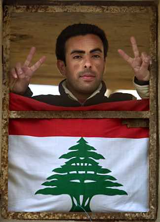 A Lebanese man flashes victory signs through the window of a Syrian intelligence building in Beirut, March 16, 2005. Syrian intelligence agents pulled out of Beirut and large parts of Lebanon Wednesday, a major step toward meeting U.S. and Lebanese opposition demands for Syria to release its grip on its small neighbor. [Reuters]