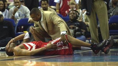 Houston Rockets guard Tracy McGrady (1) lies on the court while being attended to by athletic trainer Keith Jones during the first half of their game against the Hornets in New Orleans on Friday, March 25, 2005. McGrady suffered a strained right hip. [AP]