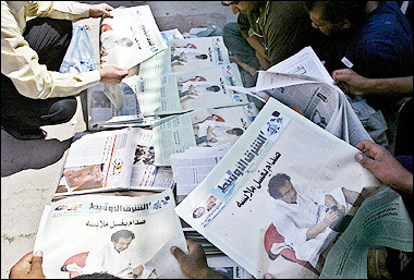 Iraqis look at the front page of an Arab daily newspaper showing a picture of former dictator Saddam Hussein washing his clothes, at a vendor's stall along street pavement in Baghdad. The US military is investigating how photographs of a jailed Saddam Hussein hit tabloids in New York and London as a British newspaper released a new shot of the former dictator amid an outcry the move violated the Geneva Conventions.(AFP