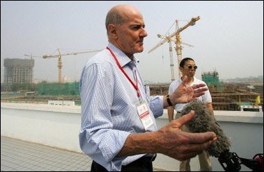 Kevan Gosper, chairman of the International Olympic Committee (IOC) press commission, speaks from a rooftop overlooking construction for the National Aquatic Center for the 2008 Olympic Games in Beijing, during a visit to venues by members of the IOC coordination commission. The construction of sporting venues for the 2008 Olympic Games was progressing on schedule and, if anything, may be going too fast, the IOC said.(AFP/
