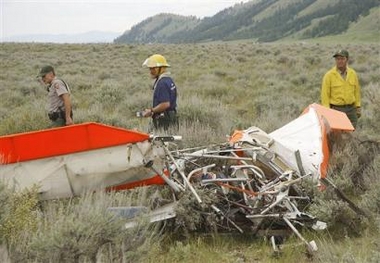 Grand Teton National Park rangers and fire personnel examine the wreckage of an ultra light aircraft that crashed Monday, June 27, 2005 just north of Jackson Hole Airport near Jackson, Wyo. The pilot, John T. Walton, a billionaire son of Wal-Mart founder Sam Walton and a member of the company's board was killed in the crash. [AP]