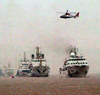 A Chinese helicopter flies over ships during the "2005 East China Sea United Search and Rescue Drill" in seas off China's financial centre Shanghai July 7, 2005. With nearly 1,000 participants as well as 30 sea-going ships and five helicopters, the drill is supposed to initiate from a collision between a large container ship and a vessel carrying dangerous chemicals. [newsphoto]
