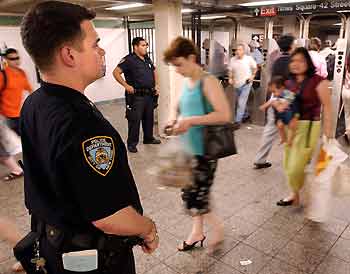 Police officer James Cullen (L) and other officers patrol the Times Square subway station in New York July 21, 2005. Commuters on New York subways will be subjected to random searches of backpacks and packages police announced just hours after the second attack on London's transit system in two weeks. REUTERS