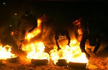 Masked Palestinian Hamas militants jump over burning tires during a training session in Jebaliya in the northern Gaza Strip, early Friday, Aug. 12, 2005.