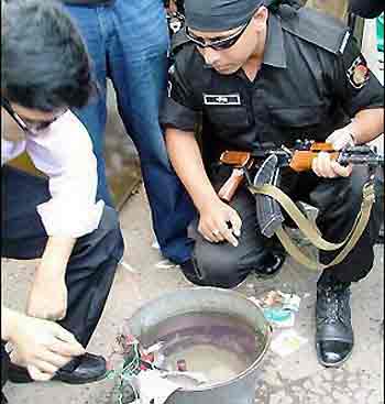 Two Bangladeshi special security force members of the 'Rapid Action Battalion' examine an explosive device in Chittagong, Bagladesh, following a series of blasts around the country.