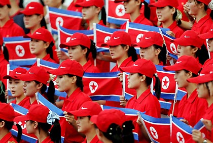 North Korean women hold their national flags as they cheer on their compatriot Kim Myong-jin in the men's 5,000 metres final at the 16th Asian Athletics Championships in Inchon, South Korea, September 4, 2005.