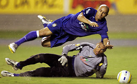 Brazilian defender Roberto Carlos (top) dives over goalkeeper Dida during their soccer training session in the northern Brazilian city of Belem October 10, 2005. Brazil will face Venezuela in a 2006 World Cup qualifier match on Wednesday. 