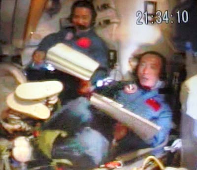 Astronauts Nie Haisheng (left) and Fei Junlong, orbiting the Earth in the Shenzhou VI spacecraft, talk through phones with their family members October 12, 2005. China launched its second manned space mission Wednesday morning. [Xinhua]