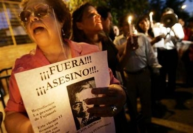 Protesters hold candles and shout slogans against former Peruvian President Alberto Fujimori outside the police training academy in Santiago, Chile, Thursday, Nov. 10, 2005, where Fujimori is being held since he was detained on an international arrest warrant after arriving on Sunday. 