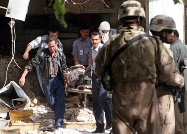 US soldiers secure the area as the body of a victim is carried from a restaurant frequented by Iraqi police, after two suicide bombers detonated themselves killing at least 33 people and seriously injuring 19, in Baghdad, Iraq, Thursday, Nov. 10, 2005.