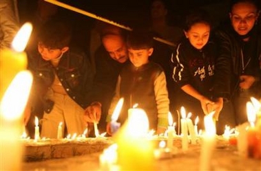 A Jordanian family lights candles outside Amman's Grand Hyatt hotel in central Amman November 10, 2005.