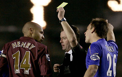 helsea's captain John Terry (R) reacts as referee Rob Styles (C) shows the yellow card to Arsenal's captain Thierry Henry (L) during their English Premier League soccer match at Highbury in London December 18, 2005.