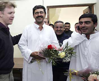 Reuters Iraq bureau chief Alastair Macdonald (L) welcomes Ali al-Mashadani (C) and Majeed Hameed (R) at the Reuters office, shortly after they were released from Abu Ghraib prison in Baghdad January 15, 2006. The U.S. military freed two Iraqi journalists who work for Reuters on Sunday after holding them for several months without charge. At least three other Iraqi journalists for international media, including a freelance cameraman working for Reuters in the northern town of Tal Afar, remain in custody. 