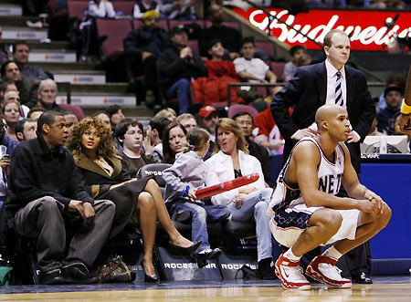 Jay-Z and Beyonce (L) sit court-side and watch the New Jersey Nets play the Indiana Pacers in their NBA game in East Rutherford, New Jersey, January 16, 2006, as Nets forward Richard Jefferson and coach Lawrence Frank (R) pause as a foul is shot in the second quarter. [Reuters]