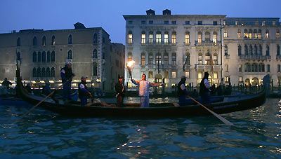 A runner carries the Olympic torch in a gondola along the Canal Grande in Venice January 17, 2006. About 10,000 torchbearers will take the flame on an 11,000-km (6,835-mile) trek to 140 cities before the 2006 Winter Olympics in the northern Italian city of Turin. 