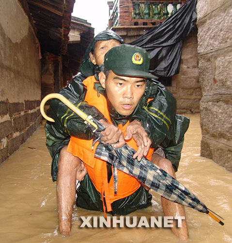  2006年7月16日，在福建省龙海市程溪镇官园村，福建省武警总队漳州支队官兵奋勇转移被洪水围困的群众。 新华社发 