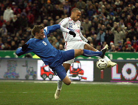 Thierry Henry (R) of France challenges Jan Durica of Slovakia during their friendly soccer match at the Saint-Denis Stade de France March 1, 2006. [Reuters]