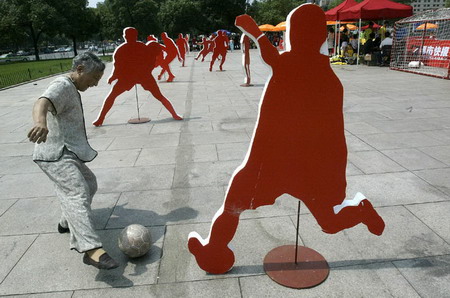 An elderly woman plays soccer beside statues on a square in Hangzhou, East China's Zhejiang Province, June 18, 2006. [Li Jiangang/Metro Express]