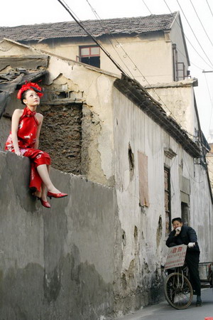 A vendor rides on a tricycle as a girl sits on the wall for a photo on a street in Hangzhou, East China's Zhejiang Province, December 20, 2006.[Zhou Tao/Metro Express]