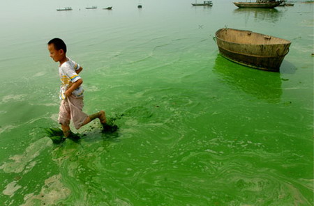 A boy walks in a polluted pond in Hefei, east China's Anhui province, July 4, 2006. [Wu Fang/ Xin'an Evening News]
