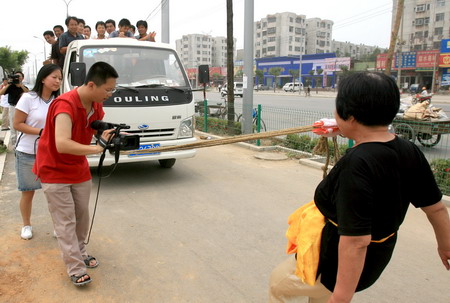 Wang Xiaobei, 72, drags a truck with her teeth during a stunt performance in Jinan, East China's Shandong Province, July 18, 2006. Wang pulled the over-four-ton truck and passengers forward over ten meters. [Zhou Qingxian/Qilu Evening News]