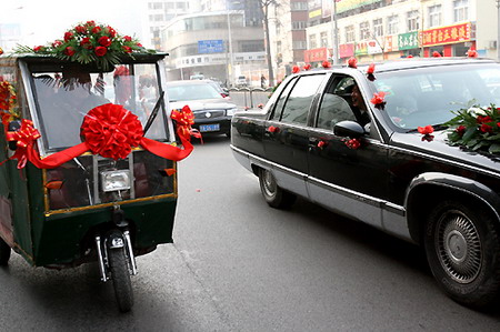 A car and a pedicab are decorated for two separate wedding ceremonies on a street in Zhengzhou, Central China's Henan Province, January 15, 2006. Yao Lin, 27, who is disabled, made a living as a pedicab driver. Some 20 of Yao's friends, mostly disabled pedicab drivers, decorated their cars for Yao's wedding. Coincidentally another wedding was being held on the same street on the same day. [Zhang Hongfei/Dahe Newspaper]