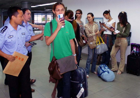 Two policemen supervise transsexuals from Thailand in Wuhan, Central China's Hupei Province, July 6, 2006. Local police in Wuhan deported seven transsexuals from Thailand.[Jin Zhenqiang/ Wuhan Evening News]