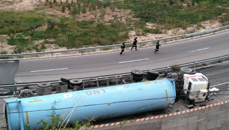  Firemen walk beside an overturned tanker on a road in Lanzhou, Northwest China's Gansu Province, September 23, 2006. [Pei Qiang/Lanzhou Morning News]