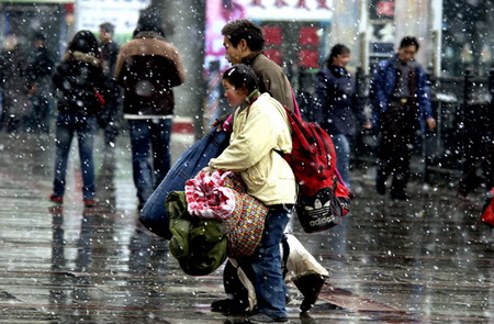  A girl carries luggage and walks with her father in the snow at a railway station in Lanzhou, Northwest China's Gansu Province, September 23, 2006. [Jiang Shenglian/Lanzhou Morning News]