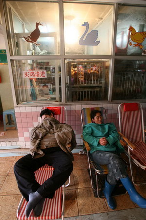 Vendors wait for customers at a meat market in Guangzhou, South China's Guangdong Province, March 7, 2006. [Ning Biao/New Express]