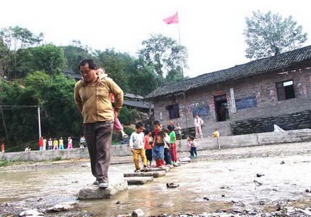  Yan Zufu, 52, carries a student and leads others through a river in Shazipo Town, Southwest China's Guizhou Province, October 13, 2006. Yan has been a teacher for 32 years in this mountainous region of the Miao ethnic minority area. In 1990, he started to prepare construction materials for a school, such as making bricks. [Zhao Hui/Guizhou Metropolis Daily]