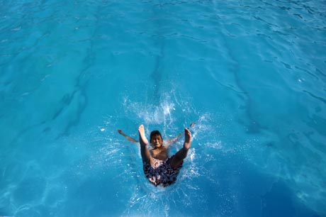 A boy jumps in a swimming pool to cool off in Skopje July 19, 2007. Macedonian authorities have declared a crisis situation across the country due to high temperatures.