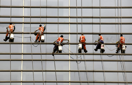 Workers clean the glass wall of a office building