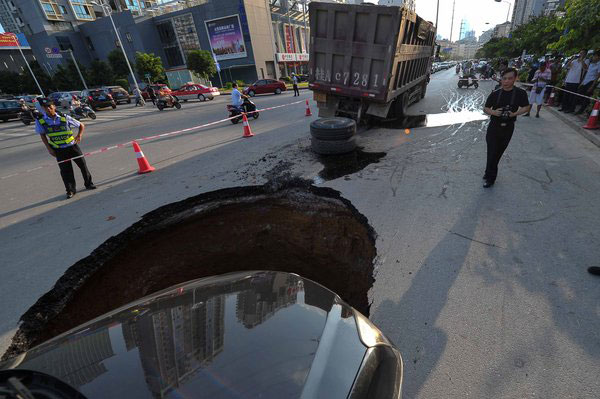 Sinkhole blocks road, damages 2 cars