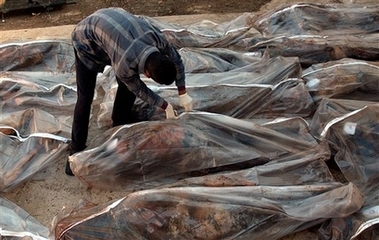 A man inspects bodies in bags outside a morgue in Baqouba, 60 kilometers (35 miles) northeast of Baghdad, Iraq, Sunday, Nov. 12, 2006. Bodies of 20 Iraqis were found in different parts of Baqouba. (AP 