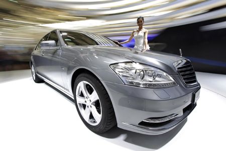 A model stands next to a new Mercedes-Benz S400 Hybrid car