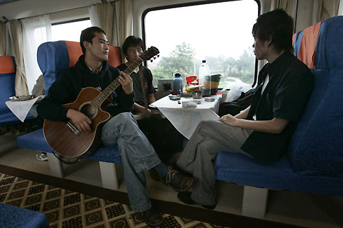 A passenger plays a guitar while friends listen on board the hard seat section of the first Beijing-to-Lhasa train as it passes Xian July 2, 2006. The 4,000-km (2,500-mile) journey will reach altitudes of over 5,000 metres (16,400 feet) on the Tibetan plateau.