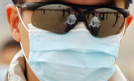 A tourist wears sunglasses and cloth mask to ward off dust as he goes sightseeing at the Tiananmen Square in the center of Beijing April 17, 2006. [Newsphoto], dust, sandstorm, weather, blu sky