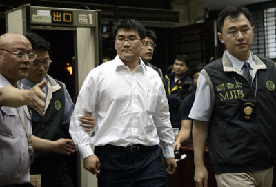 Chao Chien-ming, a doctor married to Taiwan leader Chen Shui-bian's daughter, is escorted by Bureau of Investigation agents in Taipei May 24, 2006. Chao and four members of Chen's family were questioned on Wednesday by Bureau of Investigation agents probing a snowballing insider trading scandal. [Reuters]